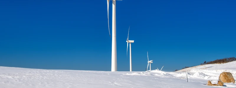 Energie : éolienne au sommet d'une montage enneigée.